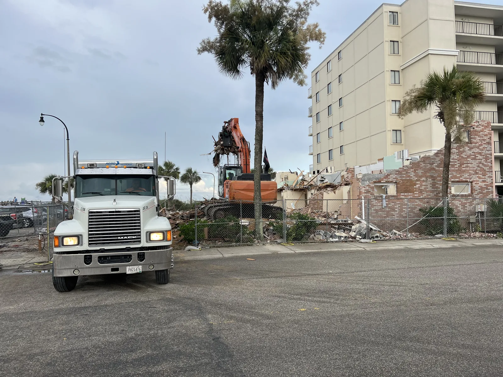 Excavator removing an exterior wall beside a coastal hotel