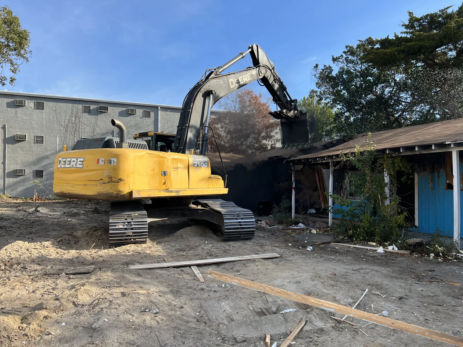 John Deere excavator removing a commercial structure