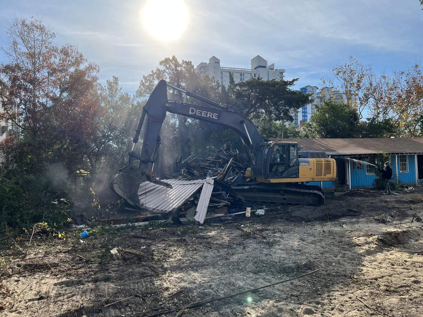 Excavator removing a structure and sorting demolition debris
