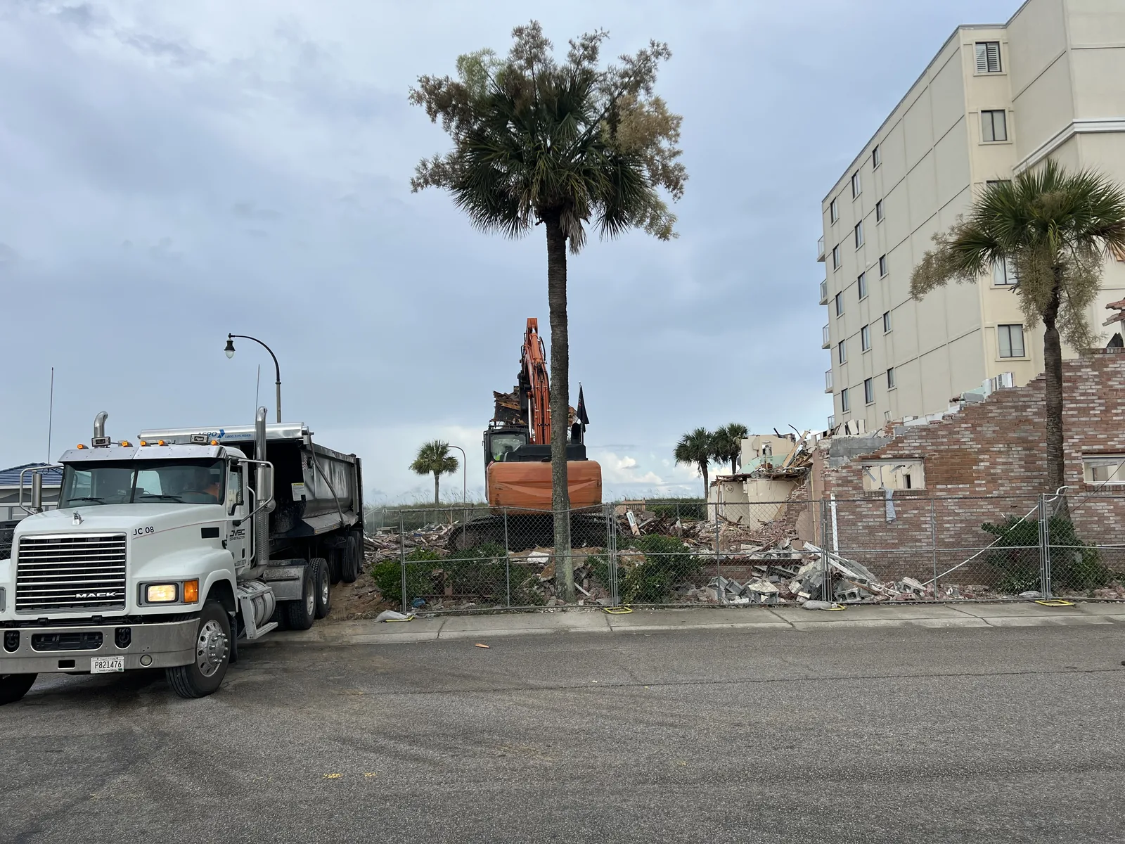 Excavator loading demolition debris beside a dump truck