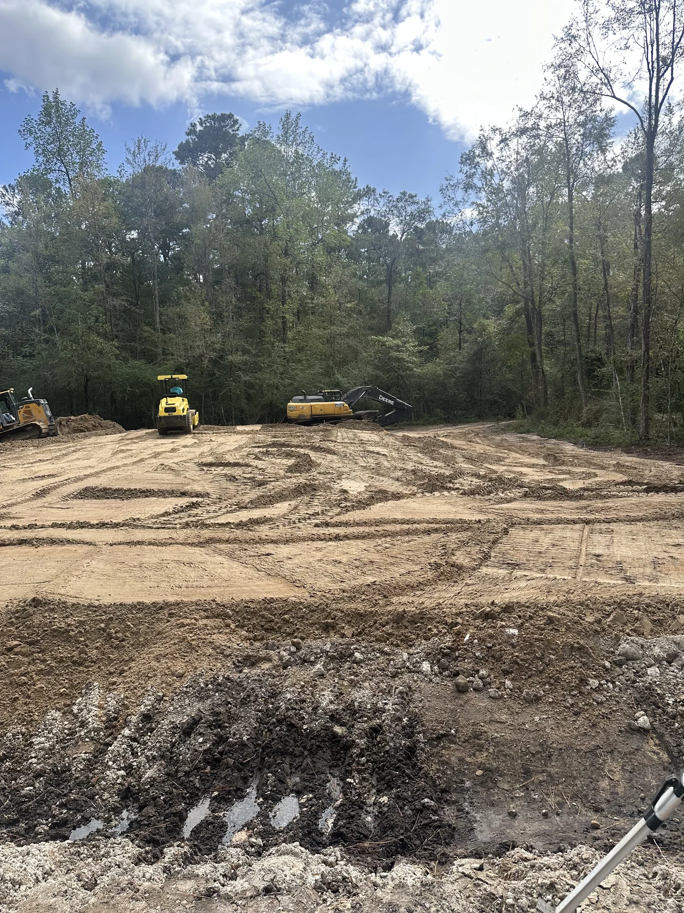 Construction equipment compacting soil across a prepared site
